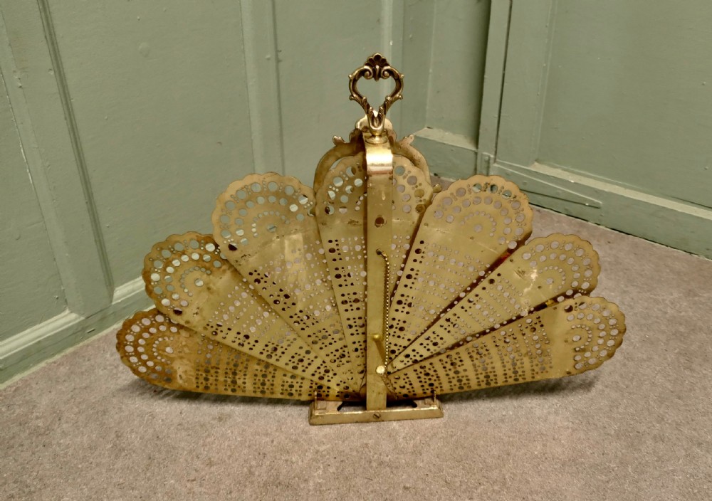 A French cast brass folding fire screen in the shape of a peacock tail with reticulated filigree blades and an ornate Rococo base. View V