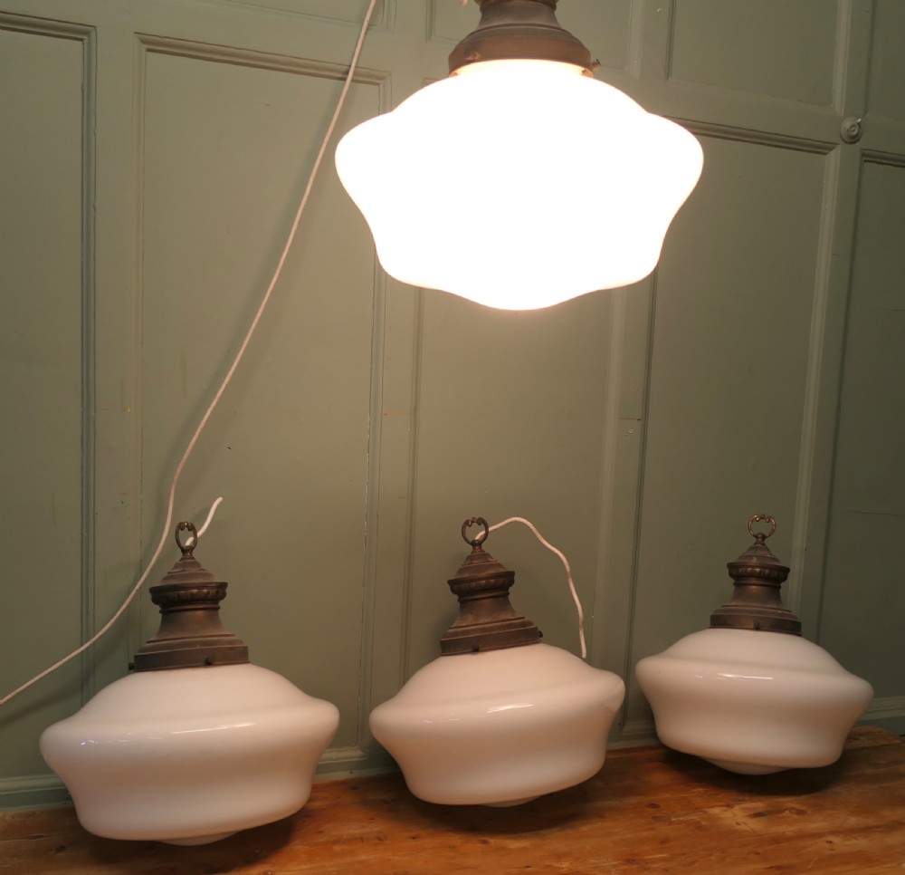 A set of four vintage industrial ceiling pendant lights featuring white opal glass shades and aged brass galleries. View III