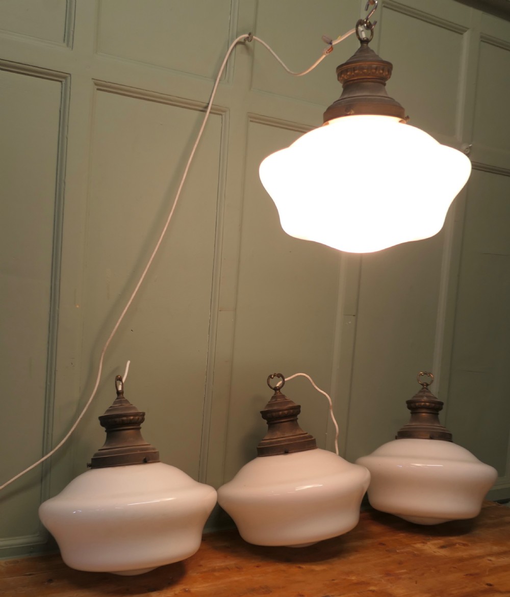 A set of four vintage industrial ceiling pendant lights featuring white opal glass shades and aged brass galleries. View IV