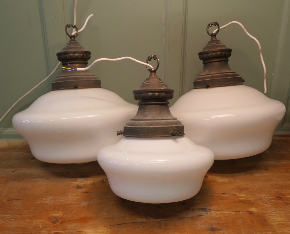 A set of four vintage industrial ceiling pendant lights featuring white opal glass shades and aged brass galleries. View VI