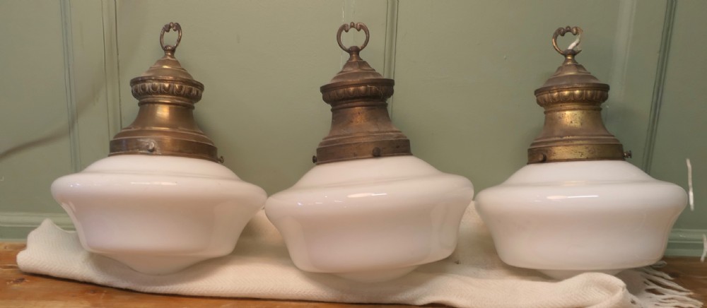 A set of four industrial ceiling lights with white opaline glass shades and patinated brass galleries featuring molded top collars and hanging rings. View II
