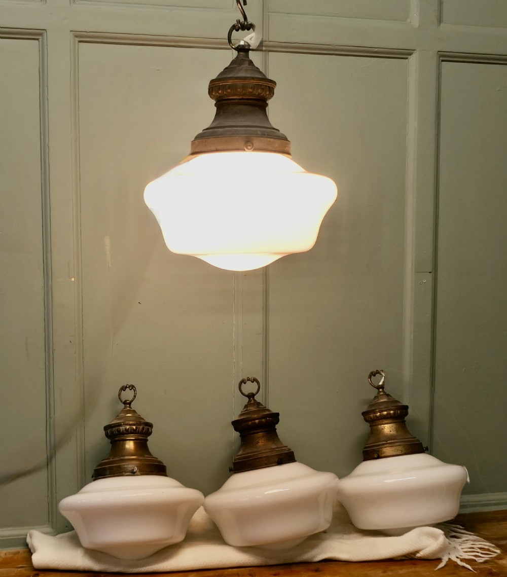 A set of four industrial ceiling lights with white opaline glass shades and patinated brass galleries featuring molded top collars and hanging rings. View III