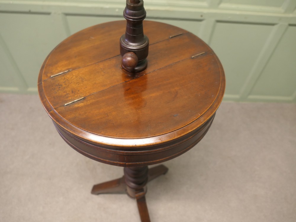 A Victorian dark mahogany freestanding shaving mirror featuring a circular frame, height-adjustable brass column, central round shelf, turned pedestal stem, and tripod legs. View V