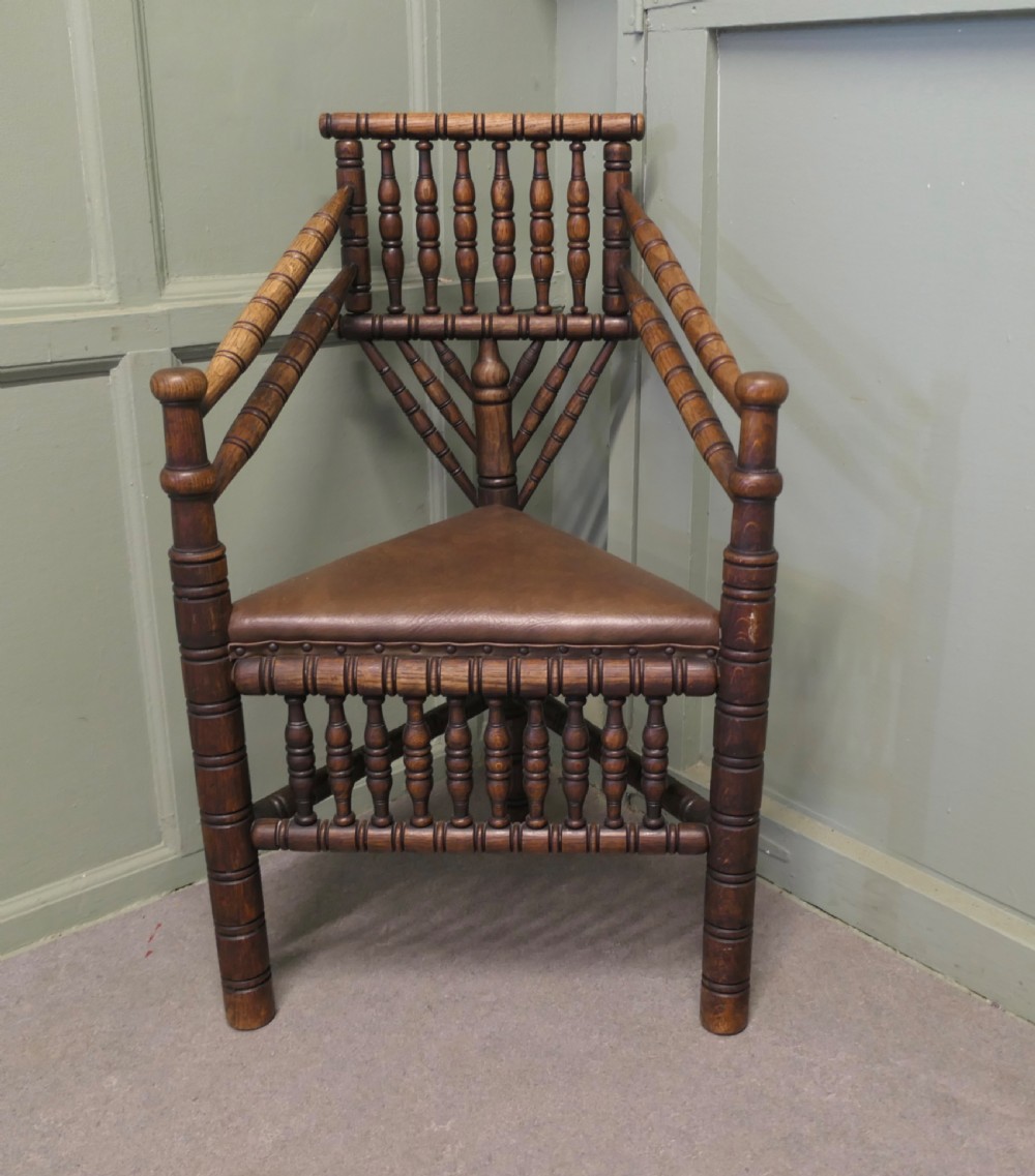A 19th-century oak turners armchair featuring extensive bobbin-turned spindles, a triangular leather seat with stud detailing, and turned legs.
