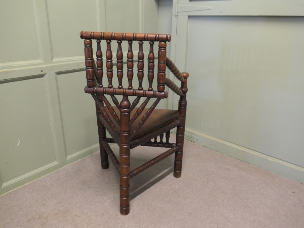 A 19th-century oak turners armchair featuring extensive bobbin-turned spindles, a triangular leather seat with stud detailing, and turned legs. View IV