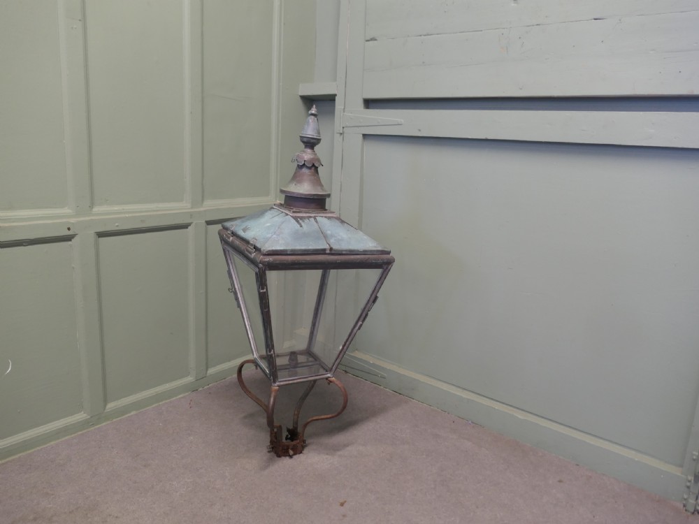 An antique Victorian copper street lantern featuring clear glass side panels, a tiered top capped with a finial, and a weathered verdigris patina. View V