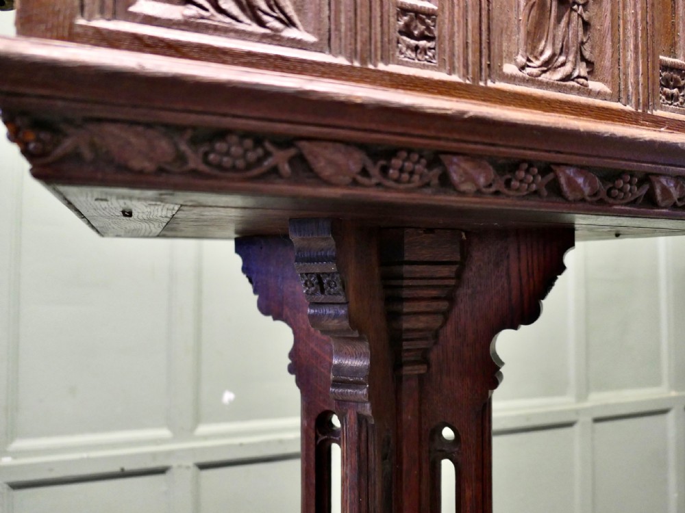 A 19th-century carved oak reading lectern featuring a sloped book rest, candle sconces, a traceried central column, and a stepped plinth base. View VII