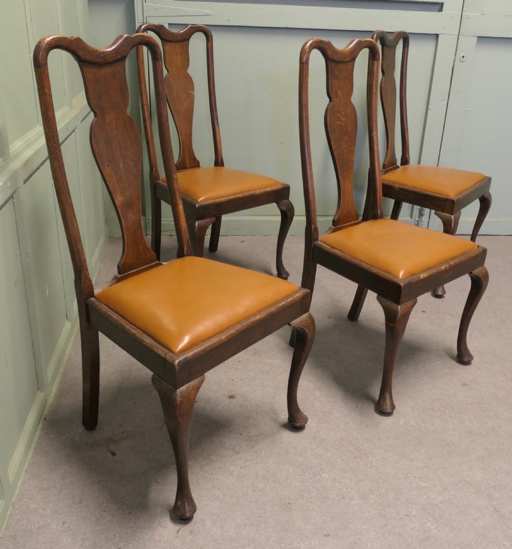 A set of four dark oak dining chairs with high vase-splat backs, tan leather drop-in seats, and front cabriole legs ending in pad feet. View VI