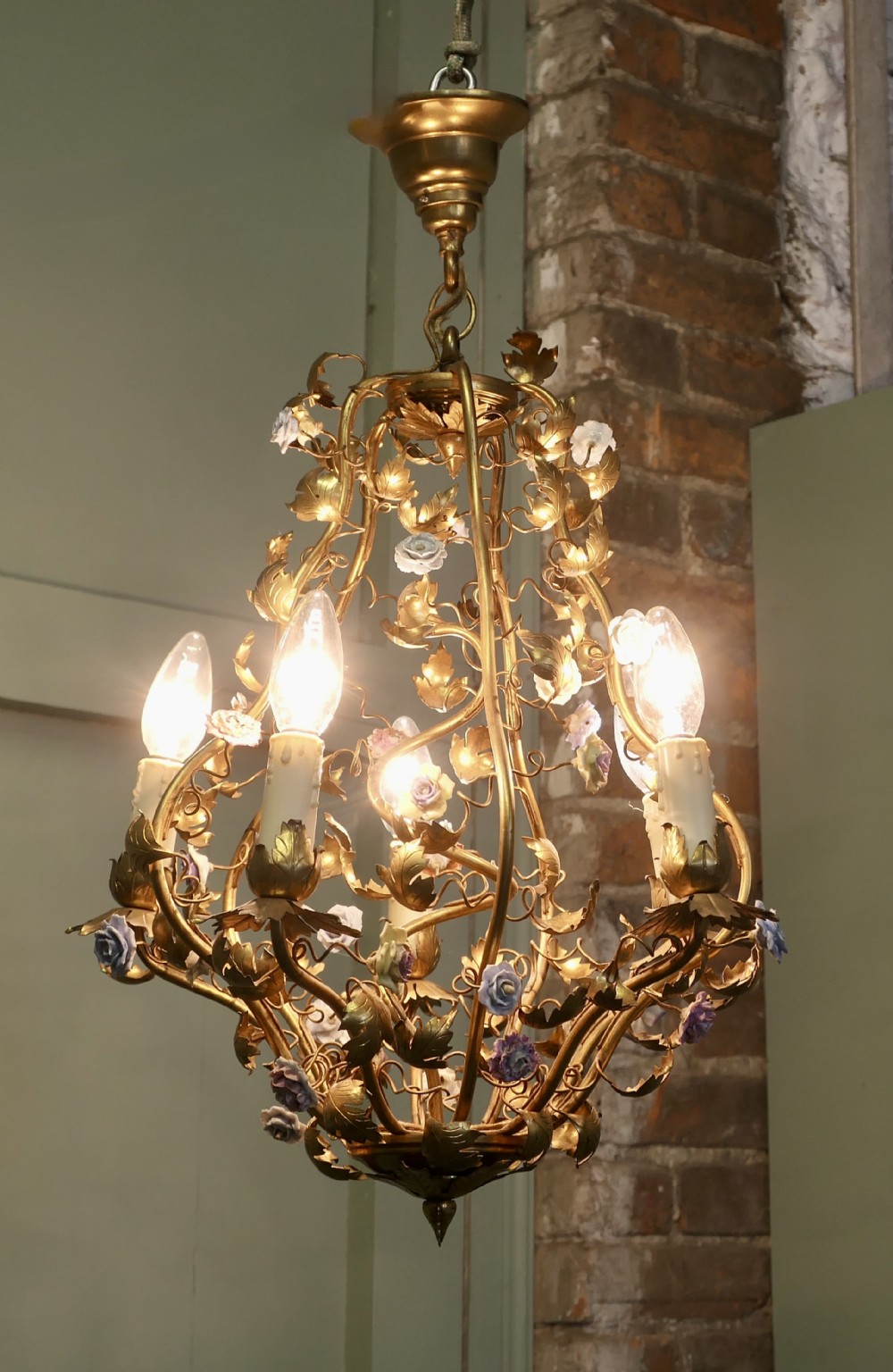 A five-bulb French toleware chandelier featuring a gilded metal frame styled with trailing leaves and multicoloured ceramic flower blooms.