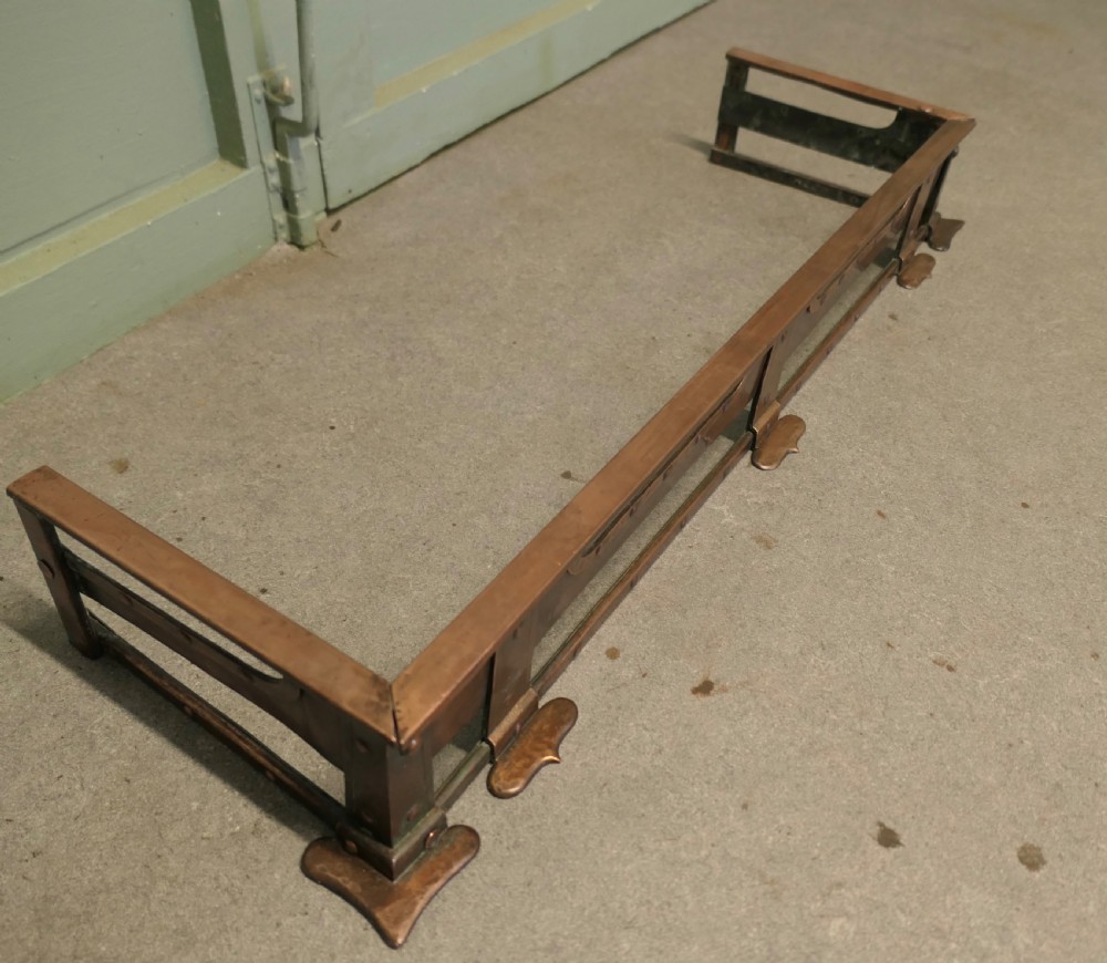 A 19th-century copper fireplace fender with hand-riveted joinery, a hammered metal texture, and raised rectangular rails. View II