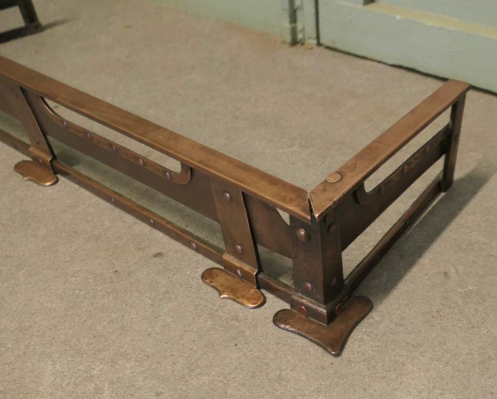 A 19th-century copper fireplace fender with hand-riveted joinery, a hammered metal texture, and raised rectangular rails. View V