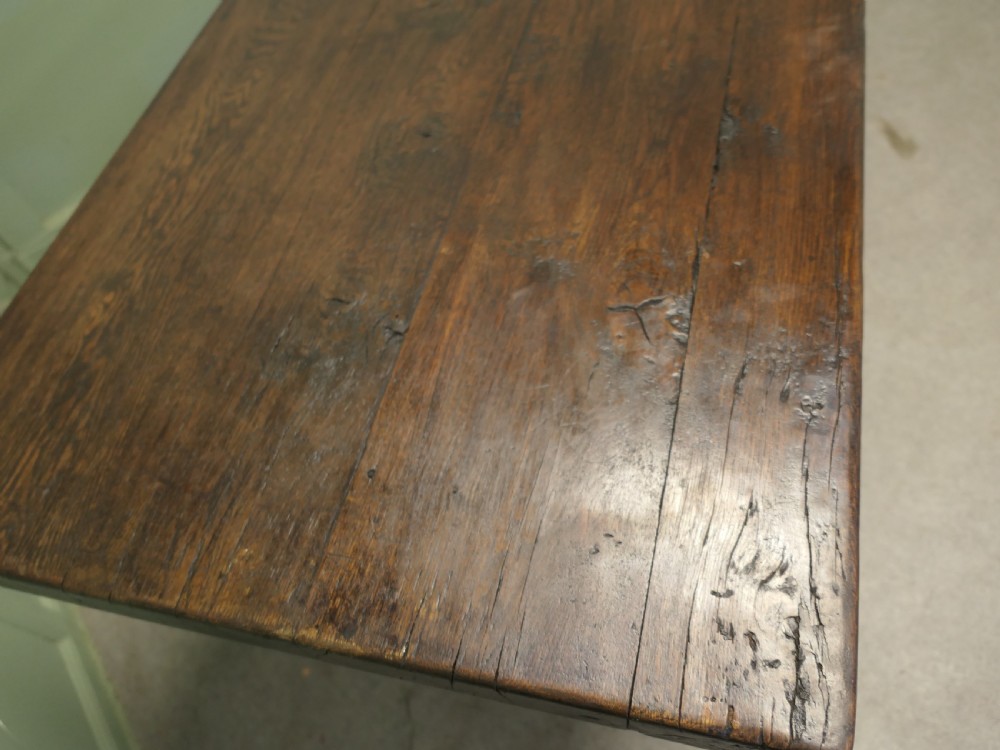 A solid dark oak French country refectory table featuring a thick rectangular top supported by twin trestle legs connected with a low central stretcher. View V