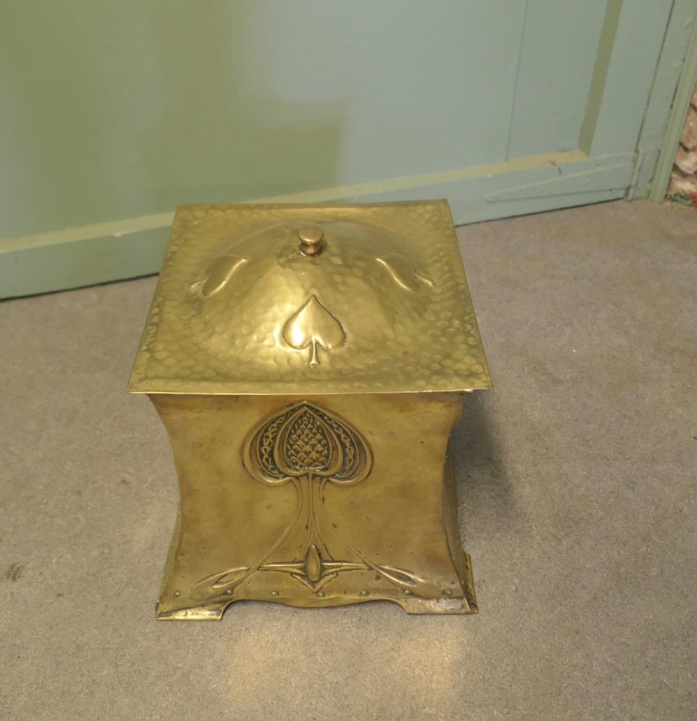 A hammered brass Arts and Crafts coal box featuring a domed lid and embossed spade-like floral motif on the front panel. View II