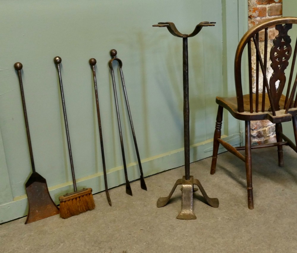 A tall hand-forged wrought iron companion set featuring a four-arm central stand with ball finials holding hanging fireplace tools over a quad-footed base. View II