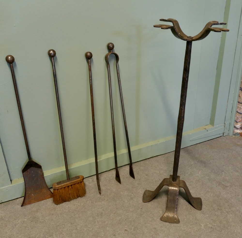 A tall hand-forged wrought iron companion set featuring a four-arm central stand with ball finials holding hanging fireplace tools over a quad-footed base. View V
