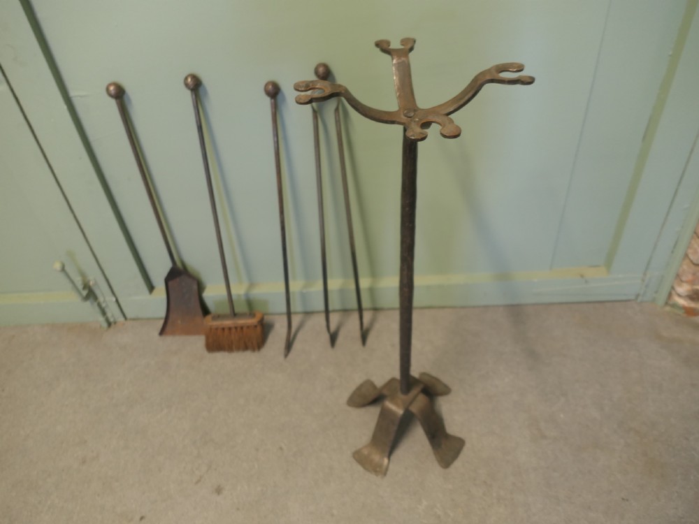 A tall hand-forged wrought iron companion set featuring a four-arm central stand with ball finials holding hanging fireplace tools over a quad-footed base. View VII