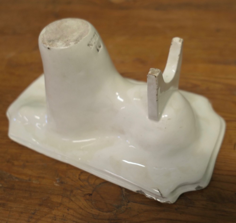 A cream glazed ceramic lion jelly mould viewed from the side showing its inverted rectangular base. View III