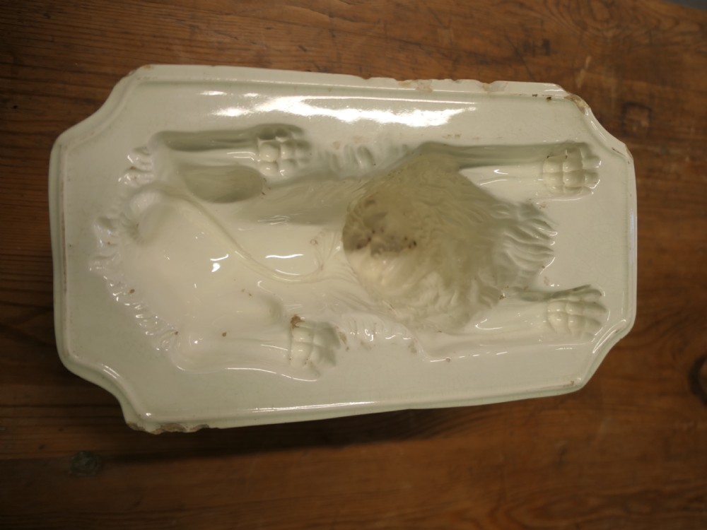 A cream glazed ceramic lion jelly mould viewed from the side showing its inverted rectangular base. View IV