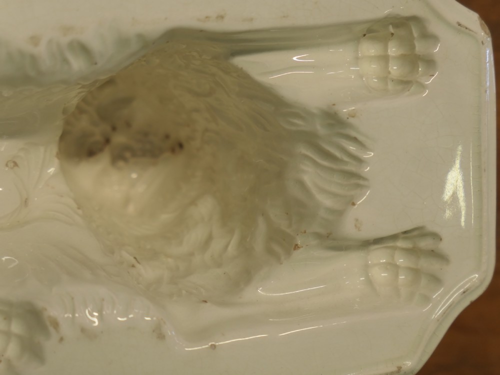 A cream glazed ceramic lion jelly mould viewed from the side showing its inverted rectangular base. View VI