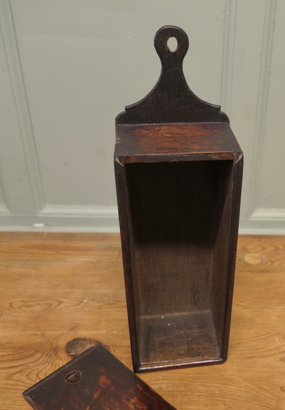 An 18th-century dark oak wall-hanging candle box featuring a shaped backboard and a sliding front panel carved with a star motif. View VI