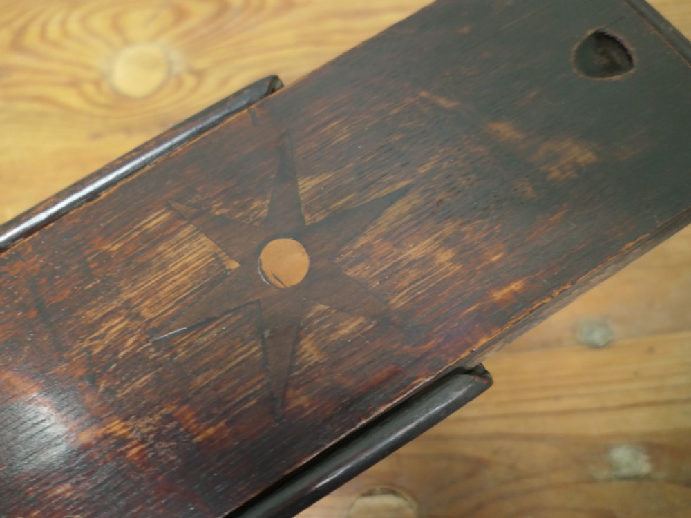 An 18th-century dark oak wall-hanging candle box featuring a shaped backboard and a sliding front panel carved with a star motif. View VII
