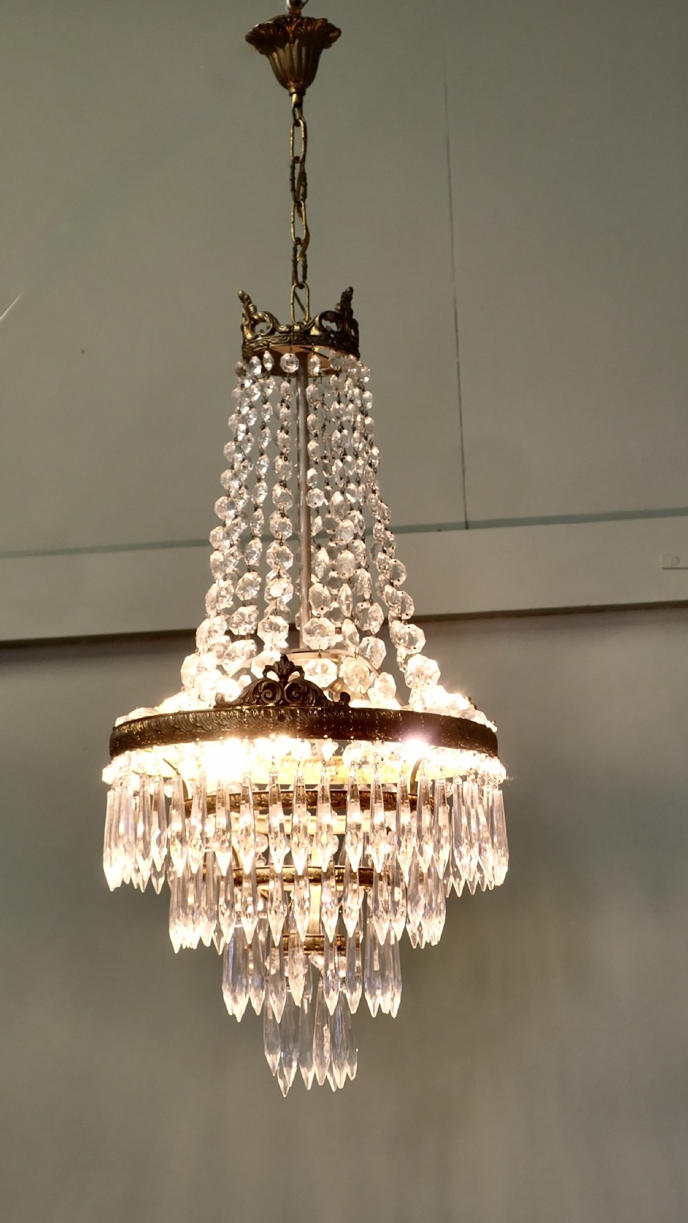 A French Empire style crystal waterfall chandelier featuring a central gilt brass band with tiered crystal drops and upper octagonal crystal bead strands.