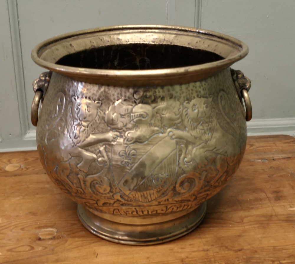 A 19th-century brass jardiniere featuring embossed heraldic lions, a shield motif with a motto, and lion head drop handles. View II