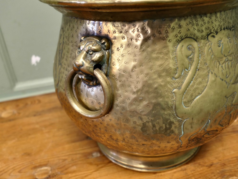 A 19th-century brass jardiniere featuring embossed heraldic lions, a shield motif with a motto, and lion head drop handles. View V