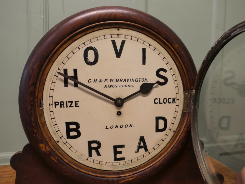 An Edwardian dark wood mantel clock featuring a round cream dial printed with Hovis Bread typography. View VII