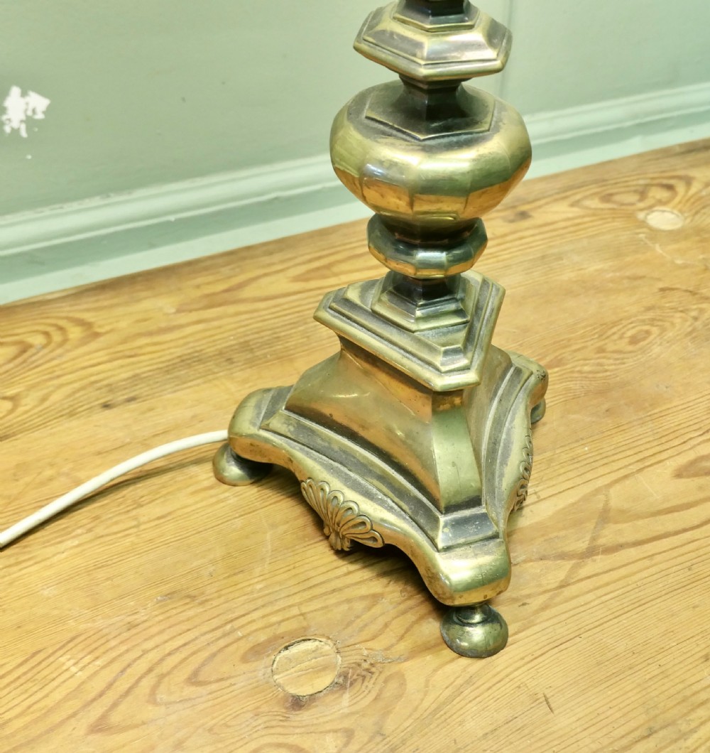 An antique brass table lamp with a stepped pedestal base, central turned column, and two angled arms supporting white frilled glass shades. View V