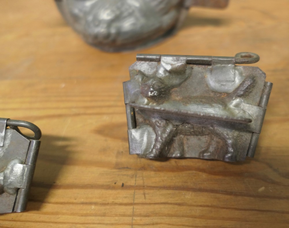 A set of four antique tinned metal chocolate moulds featuring shapes of a chicken, a dog, a cat, and a toque blanche chef hat. View II