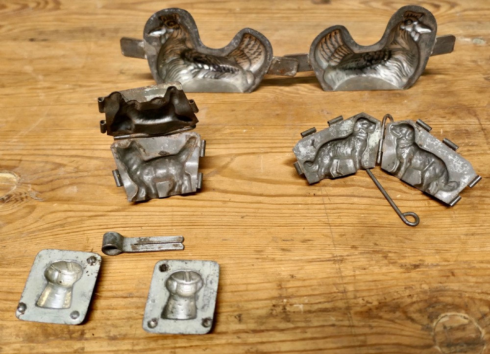 A set of four antique tinned metal chocolate moulds featuring shapes of a chicken, a dog, a cat, and a toque blanche chef hat. View VII