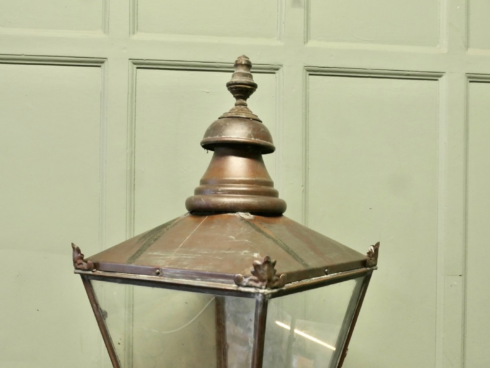 A large Victorian tapered copper lantern featuring four glass panes, a tiered top with a finial, and a wrought iron scroll base. View VI