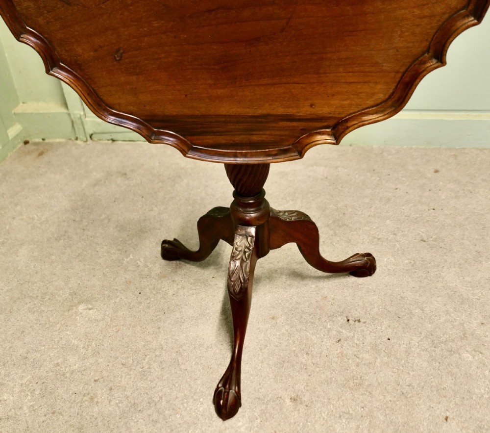 A 19th-century mahogany tilt-top wine table featuring a scalloped piecrust edge, turned central column, and carved tripod legs with claw feet. View V