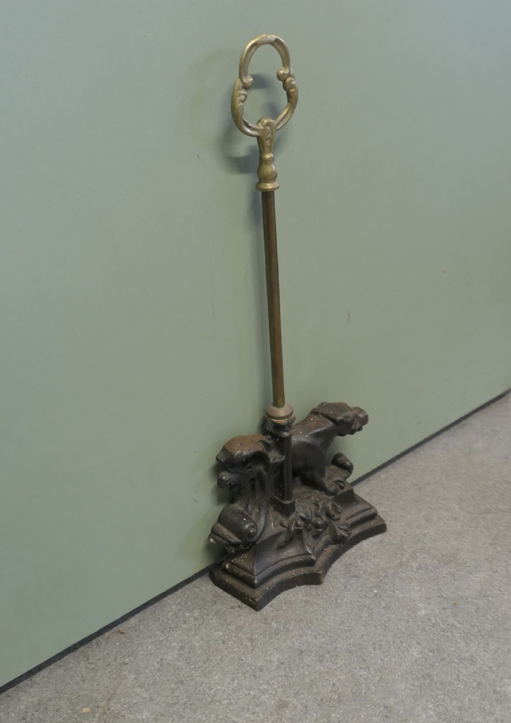 A nineteenth-century door porter featuring a heavy dark cast iron base with lion details, a tall central stem, and an oval brass loop handle.
