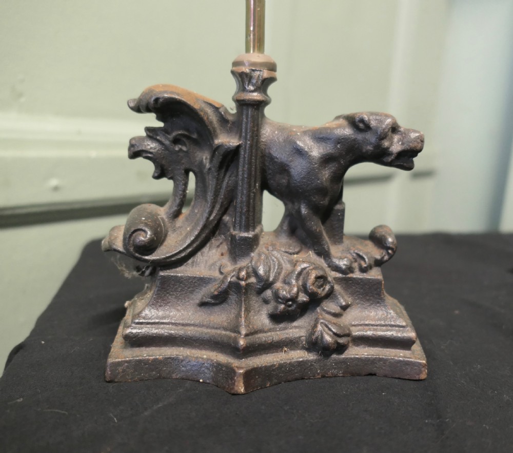 A nineteenth-century door porter featuring a heavy dark cast iron base with lion details, a tall central stem, and an oval brass loop handle. View VI
