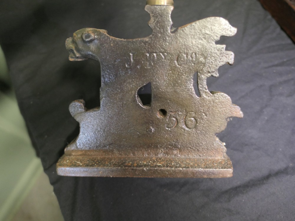 A nineteenth-century door porter featuring a heavy dark cast iron base with lion details, a tall central stem, and an oval brass loop handle. View VII