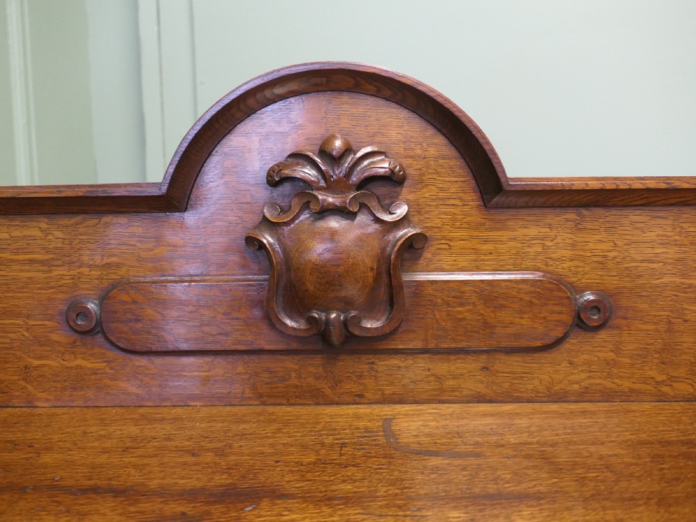 A three-tiered late Victorian carved oak buffet featuring an architectural gallery back with central carved cresting, open shelves, carved scroll supports, and castor feet. View VI
