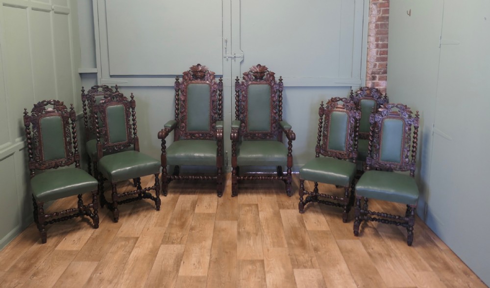 A set of ten carved oak dining chairs featuring green leather upholstery, barley twist legs, and detailed crest rails, comprising two carver armchairs and eight side chairs. View II