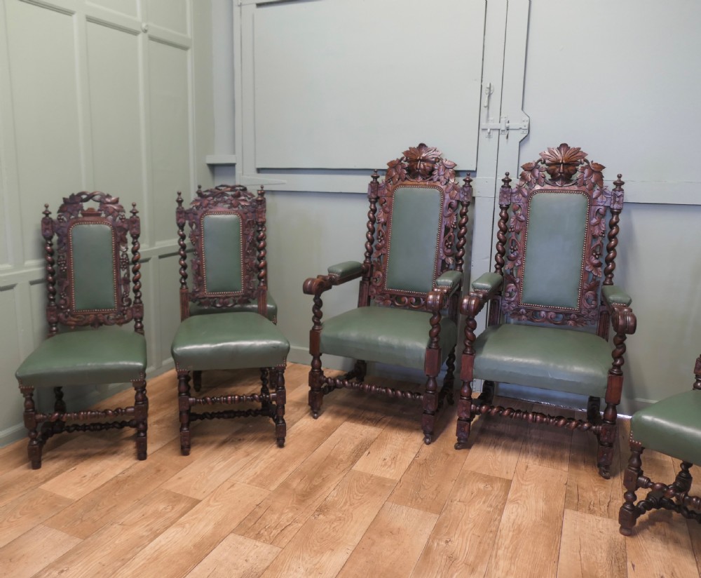 A set of ten carved oak dining chairs featuring green leather upholstery, barley twist legs, and detailed crest rails, comprising two carver armchairs and eight side chairs. View IV