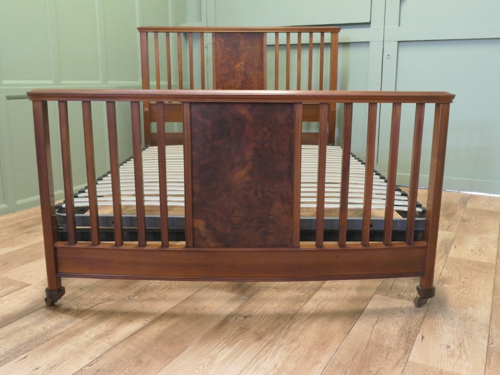 An Edwardian burr walnut double bed frame featuring a slatted headboard and footboard centered with figured walnut panels, supported by iron side rails. View VI