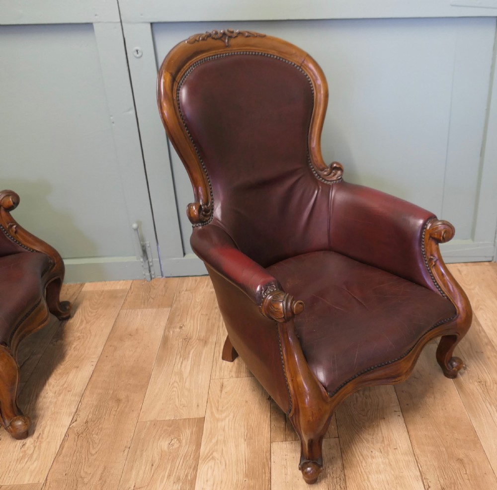 A pair of Victorian spoon back armchairs with carved mahogany frames, deep brown leather upholstery, and cabriole front legs. View VII
