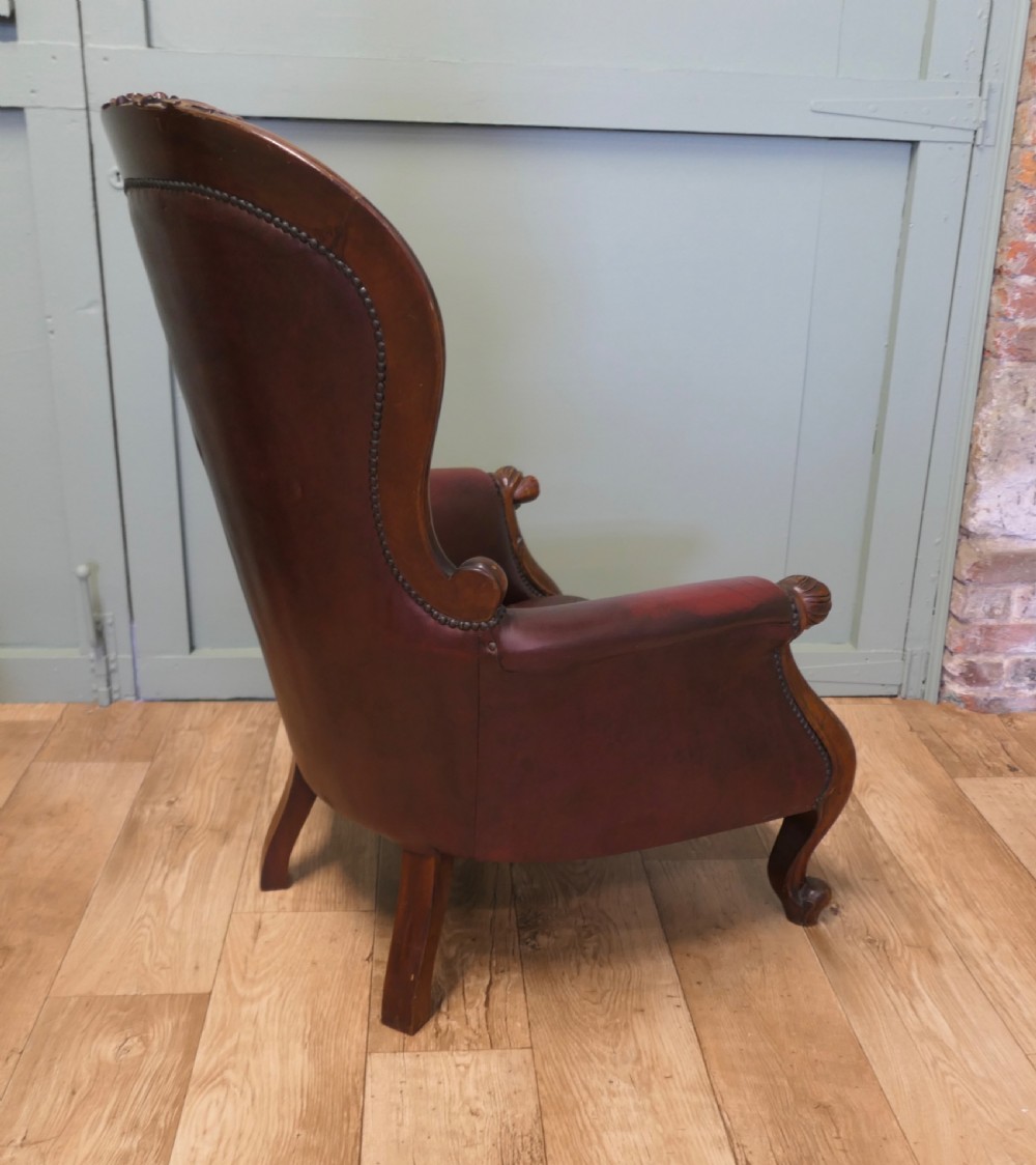 A pair of Victorian spoon back armchairs with carved mahogany frames, deep brown leather upholstery, and cabriole front legs. View VIII