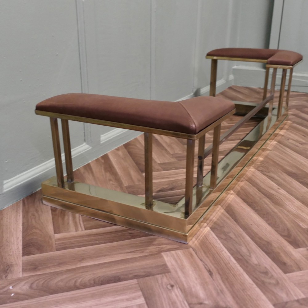 An Art Deco polished brass club fender with square upright supports and brown leather corner seats. View II
