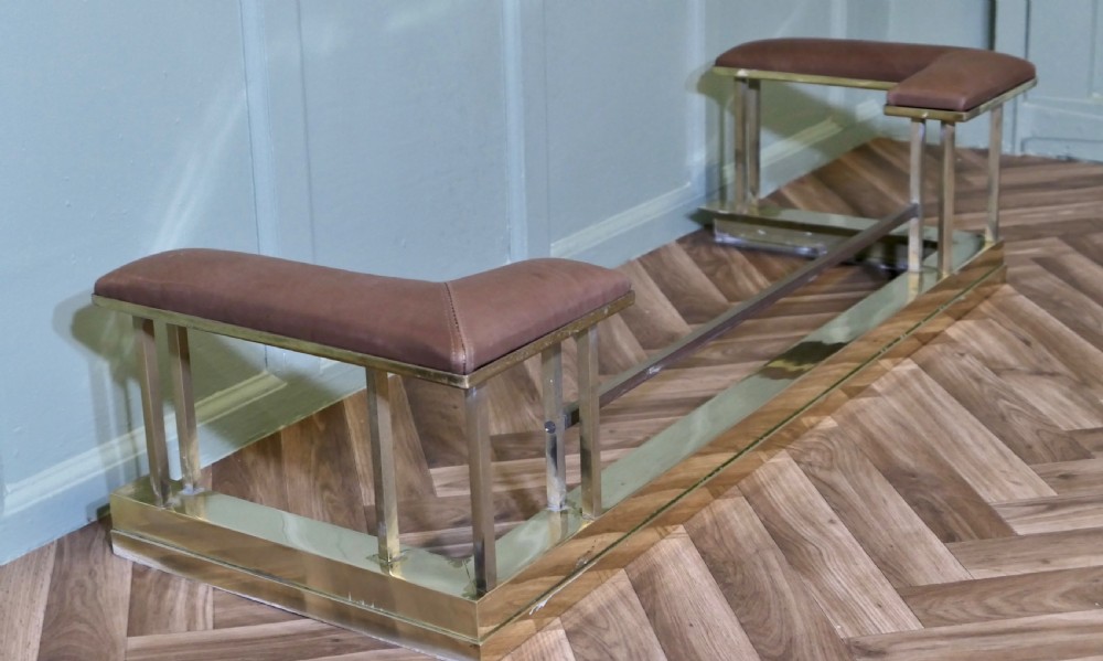 An Art Deco polished brass club fender with square upright supports and brown leather corner seats. View V