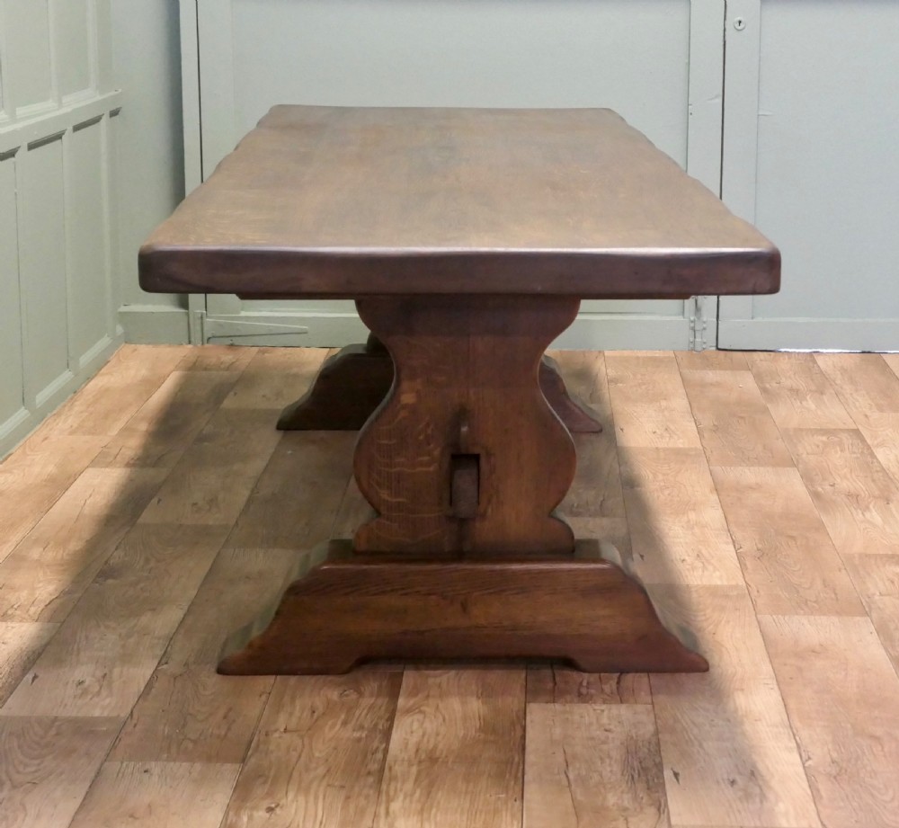 A large 19th-century French oak refectory table featuring a solid plank top, shaped trestle ends, and a central connecting stretcher. View III