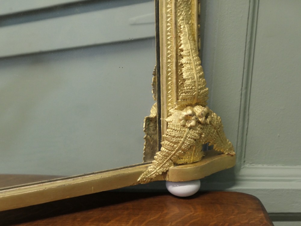 An arched gold giltwood overmantel mirror with fern leaf cresting and small corner feet. View II