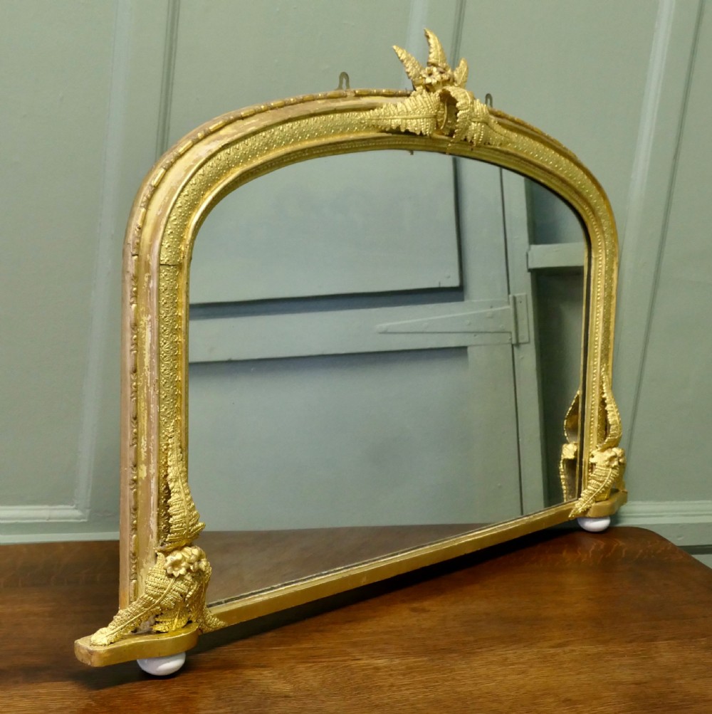 An arched gold giltwood overmantel mirror with fern leaf cresting and small corner feet. View VI