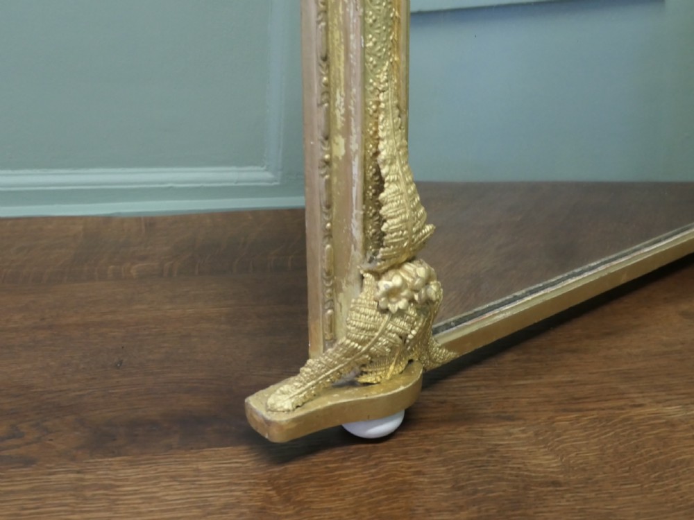An arched gold giltwood overmantel mirror with fern leaf cresting and small corner feet. View VII