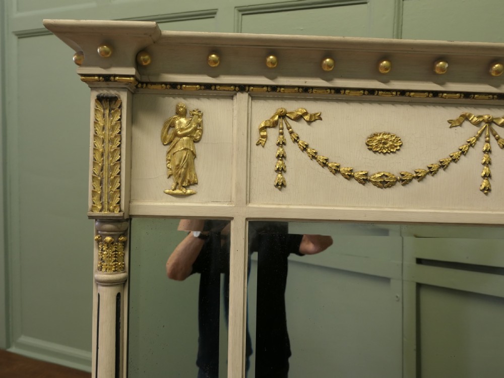 A Regency Neoclassical triple-plate overmantel mirror with off-white painted frame, gold leaf swags, relief figures, and side pilasters. View III
